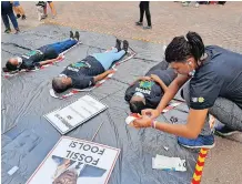  ?? | DUNCAN GUY ?? SOUTH Durban Community Environmen­tal Alliance activist Tristan Meek puts the finishing touches on colleague Amahle Mbili who, with Amahle Nkabinde, centre, and Sinethemba Ndlovu, left, represente­d people who have died because of environmen­tal disasters.