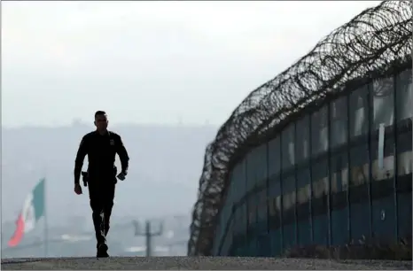  ?? AP PHOTO/GREGORY BULL ?? In this June 22, 2016, file photo, Border Patrol agent Eduardo Olmos walks near the secondary fence separating Tijuana, Mexico, (background) and San Diego. California National Guard troops have started training with the U.S. Customs and Border Patrol...