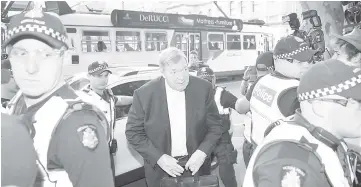  ??  ?? Pell (centre) arrives in court with a heavy police presence in Melbourne. — AFP photo