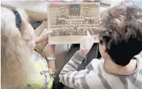  ?? ?? Elaine Wyler and Phyllis Felsenfeld look over a school photo from PS (Public School) 130 in Brooklyn during their reunion on Saturday.