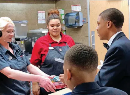  ?? [PHOTOS PROVIDED BY SHERI DOE] ?? Kruz Laviolette and Jeremiah Riley present Valentine’s chocolate and gifts to two crew members at Wendy’s as part of the Fast Food Valentine’s initiative on Wednesday in Del City.