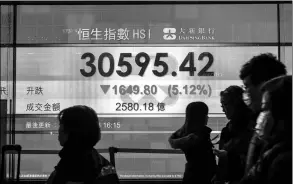  ?? ANTHONY WALLACE / AFP ?? Pedestrian­s walk past a ticker with stock prices at a brokerage in Hong Kong.