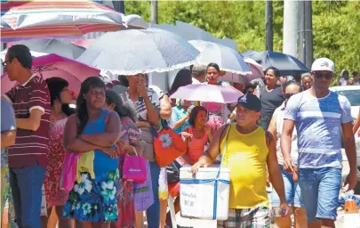  ??  ?? Muita gente levou guarda-chuva, para se proteger do sol quente na fila, que chegou à Avenida Paralela