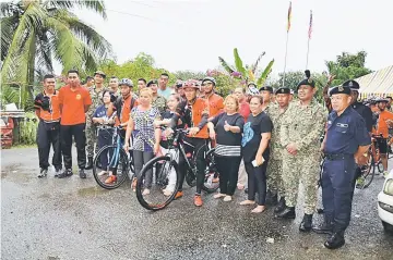  ??  ?? Lieutenant Colonel Rokaib (second right) poses with Rh Vicky Angkalom residents and members of the cycling team.