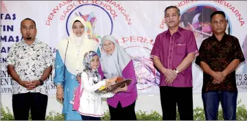  ??  ?? Dr Wan Azizah (third right) hands over school necessitie­s to one of 400 children from-low income families at the ‘Back to School’ programme in Kampung Pandan Dalam. — Bernama photo