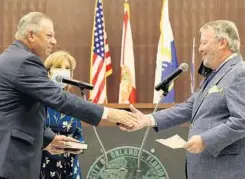  ?? ?? Commission­er Jim Gray shakes hands with Dyer after taking the oath of office Monday at the Orlando City Hall Council Chambers.