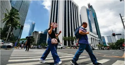  ?? ?? Pedestrian­s cross an intersecti­on in Makati City on March 27, 2024. Filipinos should brace for a scorching dry season, which could pose health risks, state weather bureau PAGASA said, days after they declared the start of the dry season. photo