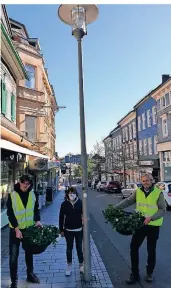  ?? FOTO: JOACHIM RÜTTGEN ?? Wim Hoogkamer, Stefanie Hofer und Peter van den Berg (v.l.) am Mittwochmo­rgen beim Aufhängen der ersten Blumenampe­l an der Kölner Straße. Die Blütenprac­ht hängt in drei Metern Höhe.