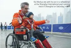  ?? — AFP ?? Kai Markus sits with his son in a wheelchair at the Shanghai Internatio­nal port running track in Shanghai on Saturday.