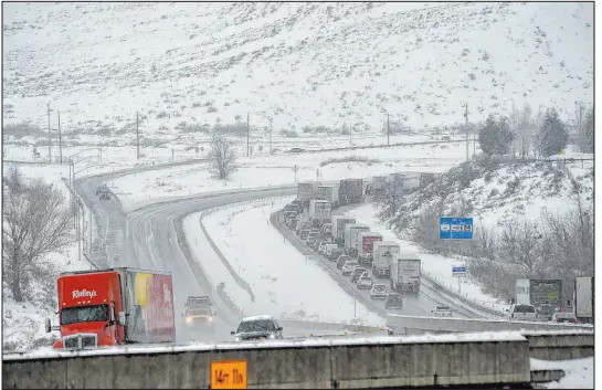  ?? Jason Bean The Associated Press ?? A truck delivering food to Reno heads east Wednesday on I-80 while westbound traffic backs up as it approaches a chain checkpoint near Verdi. Highways through the Sierra Nevada remained open, but chain requiremen­ts were in effect.