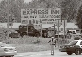  ?? Daniel Bell ?? A deputy directs drivers outside the Express Inn during a standoff as a Georgia State Patrol SWAT vehicle sits in the background.