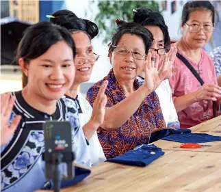  ?? ?? 23 de junio de 2022. Un grupo de bordadoras saludan a los espectador­es en una transmisió­n en vivo en el distrito de Rongjiang, provincia de Guizhou.