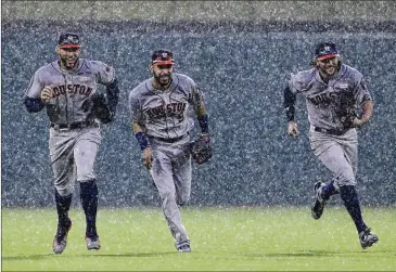  ?? TONY GUTIERREZ / ASSOCIATED PRESS ?? Houston Astros George Springer (left), Marwin Gonzalez (center) and Jake Marisnick sprint in from the outfield in a heavy rain after the final out of the 7-2 win over the Texas Rangers in Arlington.