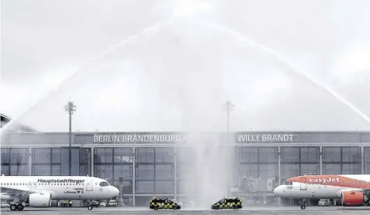  ?? Dpa-BILD: Kappeler ?? Mit einer Wasser-Fontäne begrüßte die Flughafen-Feuerwehr die ersten beiden Flugzeuge am BER.