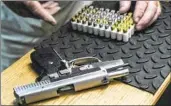  ?? Bebeto Matthews Associated Press ?? A SHOOTING range owner in New York prepares to load bullets into a semiautoma­tic handgun.