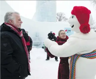  ?? THE CANADIAN PRESS ?? Premier Philippe Couillard — watching his wife Suzanne Pilote dance with Bonhomme during a visit to Quebec City Saturday — says the province has negotiated gains with the provinces medical specialist­s.