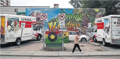  ?? R.J. JOHNSTON TORONTO STAR ?? The Jimmy Wisdom Way mural is seen behind U-Haul trucks. According to the city of Toronto, there are 116 developmen­t applicatio­ns for Little Jamaica, some of which would be large, new developmen­ts.