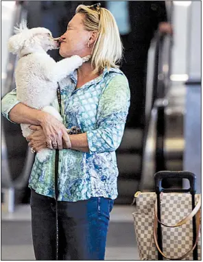  ?? Arkansas Democrat-Gazette/MITCHELL PE MASILUN ?? Dottie Arn of Hot Springs gets kisses from her dog, Amber, at Bill and Hillary Clinton National Airport/Adams Field after returning home Friday from California. The airport expects to finish this year having served more than 2 million passengers.