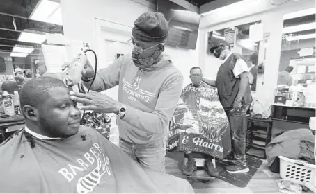  ?? JULIO CORTEZ/AP ?? Kevin Fitzhugh, center left, cuts the hair of Mabreco Wright, left, as Wallace Wilson, right, cuts the hair of James McRae on April 9 in Maryland.