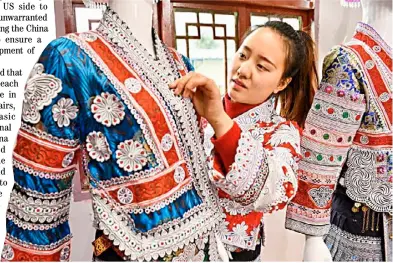  ?? XINHUA ?? YANG Wenli of Miao ethnic group arranges Miao costumes at the relocation site for poverty-stricken people in Huawu Village, Qianxi County of Bijie City, southwest China’s Guizhou Province as various industries meet booming developmen­t this year.