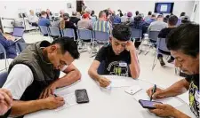  ?? Kin Man Hui/Staff photograph­er ?? Agustin Martinez, left, and his son, Yahel, write their remarks for a Texas Parks & Wildlife Commission hearing in Austin.