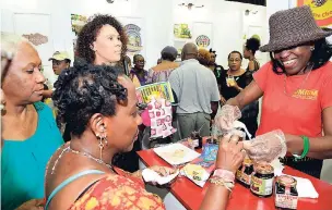  ??  ?? June Gottgens (right) showcases samples of her product, umium coconut chocolate spread, at Expo Jamaica 2018 at the National Indoor Sports Centre and National Arena, yesterday.