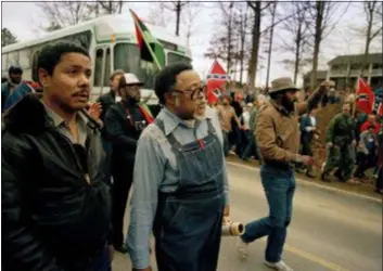  ?? GENE BLYTHE — THE ASSOCIATED PRESS ?? In this photo, Atlanta city councilman, the Rev. Hosea Williams, in overalls, leads a march against efforts to keep Forsyth County in Georgia all white past counter-protesters near Cumming, Ga., as a crowd waves Confederat­e flags and jeer the marchers. Racial stereotype­s and racist imagery in popular culture seemed to be everywhere in the chaotic 1980s when future Virginia Gov. Ralph Northam and future Attorney General Mark Herring admitted dressing up in blackface.