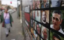  ?? ?? A womans walks past a wall bearing a portrait of rescued Israeli-Argentinia­n hostage Fernando Simon Marman (centre right), along with pictures of other Israelis held captive in Gaza by Hamas, in Jerusalem.