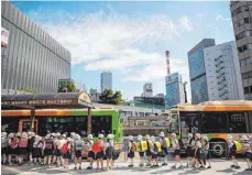  ?? FOTO: AFP ?? Nicht schick genug? Kinder im Tokioter Viertel Ginza auf dem Weg zur Schule – künftig sollen sie Armani-Uniformen tragen.