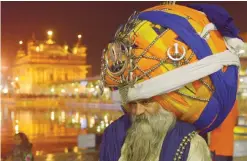  ??  ?? AMRITSAR: An Indian Sikh Nihang (a traditiona­l Sikh religious warrior) Baba ‘Avtar’ Singh wears an oversized giant traditiona­l turban as he pay respects at the Golden temple in Amritsar on Tuesday on the eve of the Indian festival of Diwali, the...