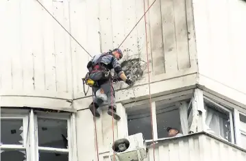  ?? AP ?? Investigat­ors inspect an apartment building after a suspected Ukrainian drone struck it in Moscow on Tuesday.