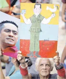  ?? FOTO: AP ?? Un hombre sostiene una pintura de Hugo Chávez.