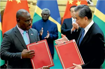  ?? GETTY IMAGES ?? Solomon Islands Foreign Minister Jeremiah Manele and Chinese Foreign Minister Wang Yi celebrate signing an agreement at the Great Hall of the People in Beijing. Security partnershi­ps with South Pacific nations, including the Solomons, have been cited in a new report that says Beijing is increasing its influence throughout the Commonweal­th.