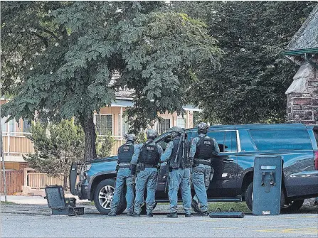  ?? JULIE JOCSAK THE ST. CATHARINES STANDARD ?? The Niagara Regional Police Police tactical unit stands outside a downtown St. Catharines building following a triple shooting Thursday afternoon.