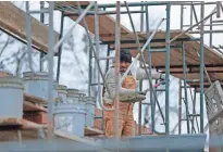  ?? MIKE DE SISTI MILWAUKEE JOURNAL SENTINEL ?? A worker lays bricks for a new wall at the rebuilt BP gas station in Sherman Park.