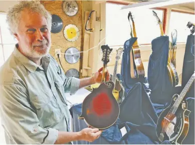  ?? PHOTOS BY JOHN MCCASLIN ?? String instrument maker Steve Marquisee and one of his classic mandolins handmade in Keyser Run. Below left, Jonathan Marquisee holds a handwritte­n descriptio­n of the Florentine style mandolin his father crafted for him.