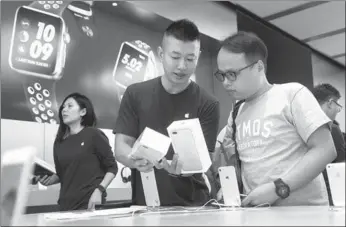  ?? AFP ?? An employee shows a customer the new iPhone 7 during the opening day of sales at an Apple store in Hong Kong on Friday.