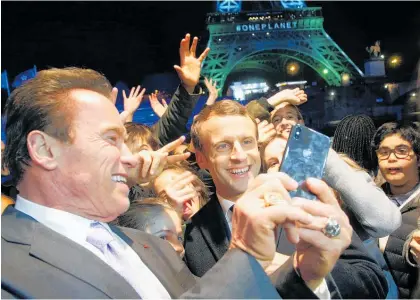  ?? Picture / AP ?? The message at the summit may have been bleak but actor and former California Governor Arnold Schwarzene­gger (left) and Emmanuel Macron were all smiles as they posed for a selfie later in the evening.