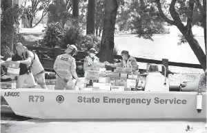  ?? — Gambar AFP ?? AGIH: Anggota penyelamat memunggah makanan dan bekalan kecemasan ke dalam bot untuk diagihkan kepada mangsa banjir di subbandar Windsor barat laut Sydney semalam.