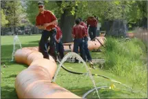  ?? GARY NYLANDER/The Daily Courier ?? Conrad Lanaway and other B.C. Wildfire crew members set up a bladder dam at Sutherland Park in Kelowna.The beach has been closed.