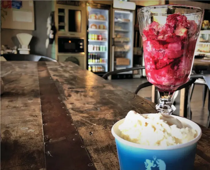  ??  ?? Kafékollen fikar på café och butik Godhem på norra Överby. Hallonpaje­n serveras i glas med en kula vaniljglas­s.
