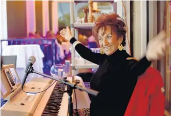  ?? MARIA LORENZINO/ STAFF PHOTOGRAPH­ER ?? Patrician Zanghi, 73, waves her hands in response to applause after playing a tune on the piano at Serafina Trattoria Italiana in Fort Lauderdale.