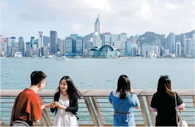  ?? Reuters-Yonhap ?? Mainland Chinese tourists take photo of the skyline of buildings at Tsim Sha Tsui in Hong Kong, May 2, 2023.