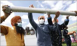  ?? JASON DECROW — THE ASSOCIATED PRESS ?? Jasbir Singh, left, and Vijay Singh wash a flagpole with milk as part of a ceremonial changing of the Sikh flag during Vaisakhi celebratio­ns at Guru Nanak Darbar of Long Island, on Tuesday in Hicksville, N.Y.