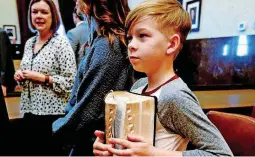  ??  ?? Finn Brockman, 10, holds the Bible used for father Scott Brockman’s swearing-in ceremony as special judge for Cleveland County.