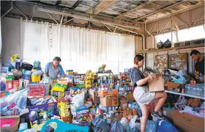  ?? ANA RAMIREZ U-T ?? On Monday in Jacumba Hot Springs, Michael Aiau (left) and others organize food and other donations as part of a community-led effort for migrants in holding areas awaiting processing of their appeal for asylum.