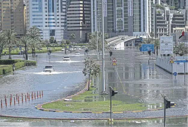  ?? ?? Cars drive in a flooded street in Sharjah in Dubai, as the Middle East’s financial centre has been paralysed by the torrential rain that caused floods across the UAE and Bahrain and left 18 dead in Oman