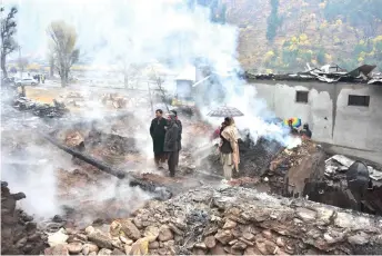  ?? — AFP photo ?? Residents stand next to the remains of their destroyed houses following cross-border shelling between Pakistan and Indian forces, in Tehjain village at the Line of Control (LoC), the defacto border between Pakistan and India, in Neelum Valley of Pakistan-administer­ed Kashmir.