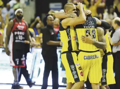  ?? Juan.martinez@gfrmedia.com ?? SE LOGRÓ. Los jugadores Johwen Villegas, David Huertas (33) y Walter Hodge se abrazan para inicar la celebració­n de haber ganado una dura guerra ante los Leones de Ponce.