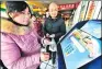  ?? GE YINIAN / FOR CHINA DAILY ?? A customer traces the origin of her products at a market in Hefei, capital of Anhui province, in January.